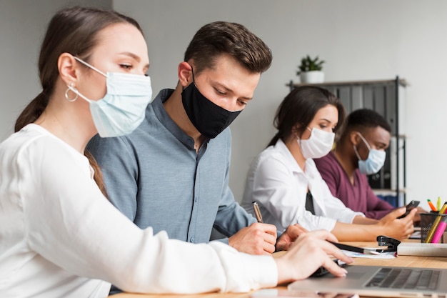 People in the office working during pandemic with masks on Free Photo